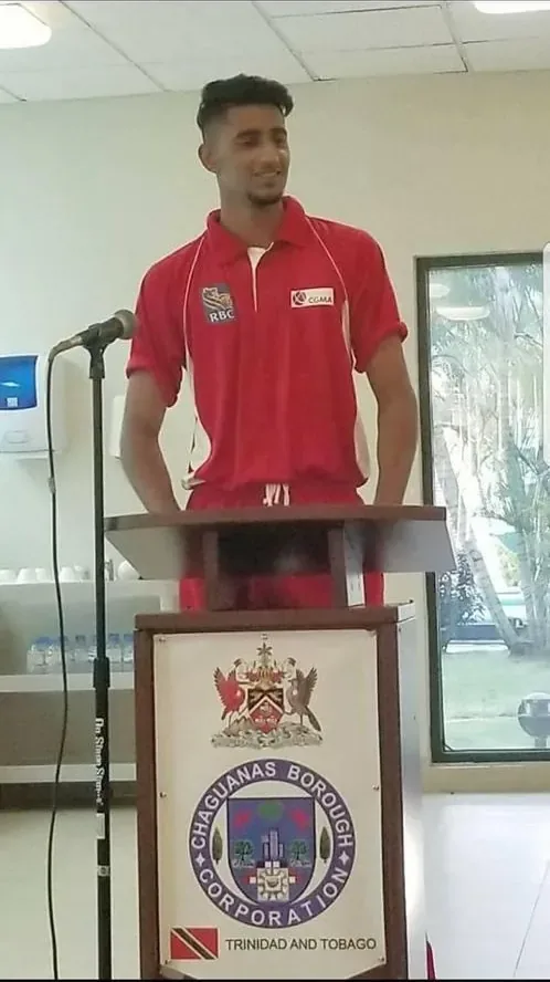 Wasiq speaking at a podium during the cricket tour in Trinidad